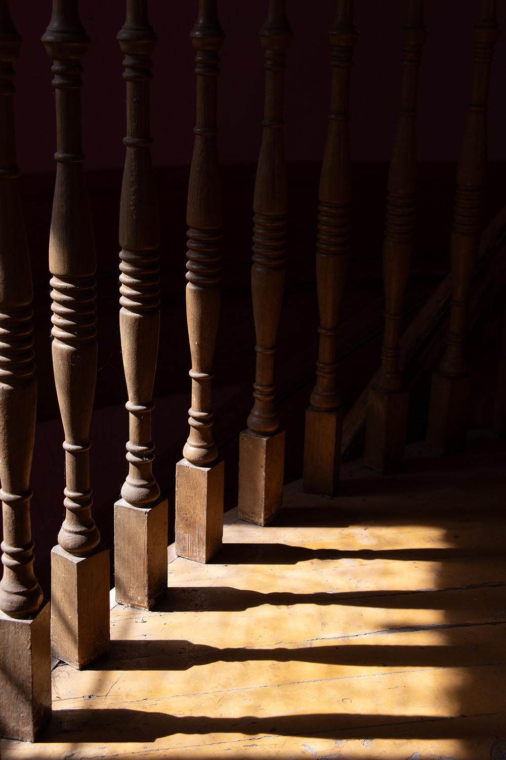 Preserving the Legacy of Colorado Cattle Country: The Castle Alonzo Hartman Built Photo of stair railing wood work with dramatic lighting in Gunnison Colorado's historic Hartman Castle